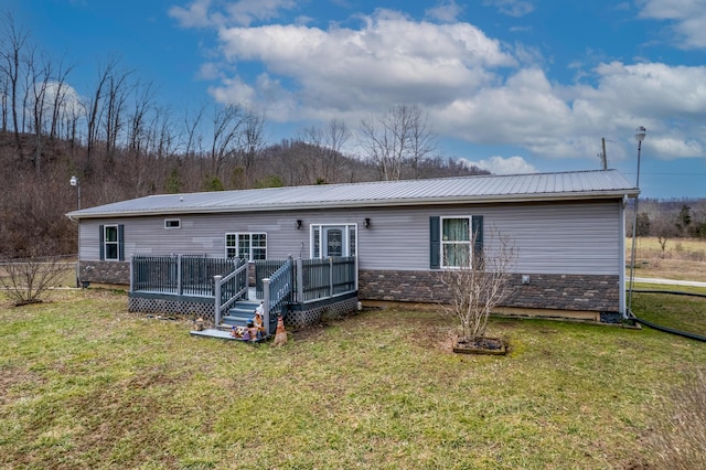 back of house with stone siding, a lawn, metal roof, and a deck