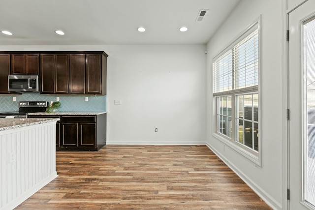 kitchen featuring visible vents, light wood-type flooring, stainless steel appliances, dark brown cabinetry, and tasteful backsplash