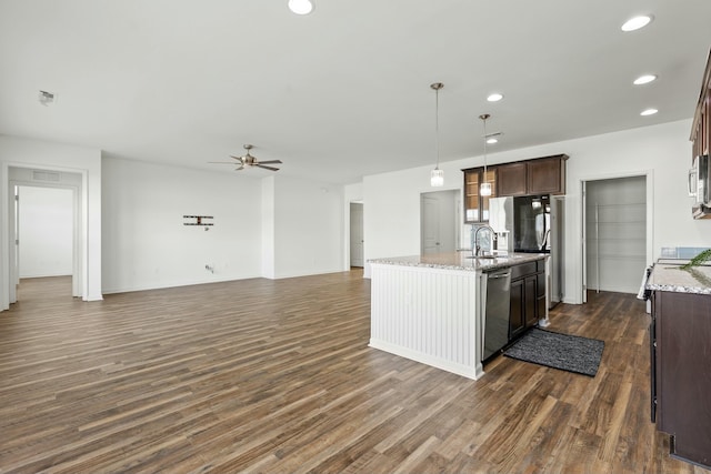 kitchen with a kitchen island with sink, open floor plan, appliances with stainless steel finishes, and dark wood-style flooring