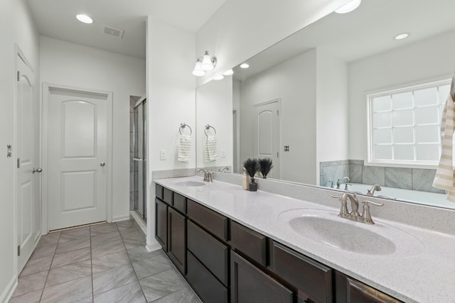 full bath with double vanity, visible vents, a shower stall, and a sink