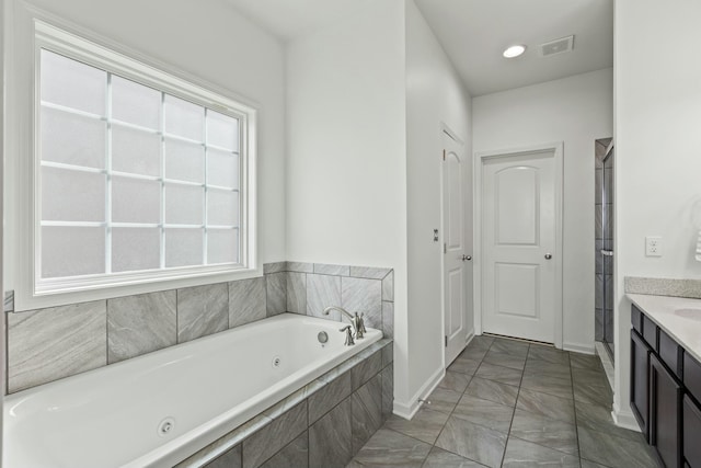 bathroom featuring vanity, a tub with jets, baseboards, visible vents, and a stall shower