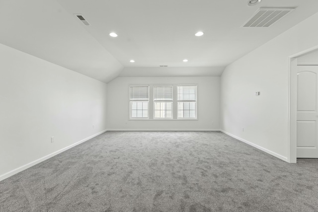 carpeted empty room with vaulted ceiling, baseboards, and visible vents