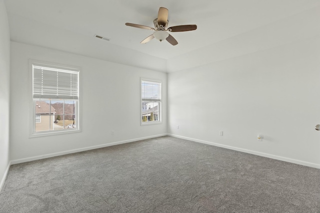 carpeted empty room with visible vents, baseboards, and ceiling fan