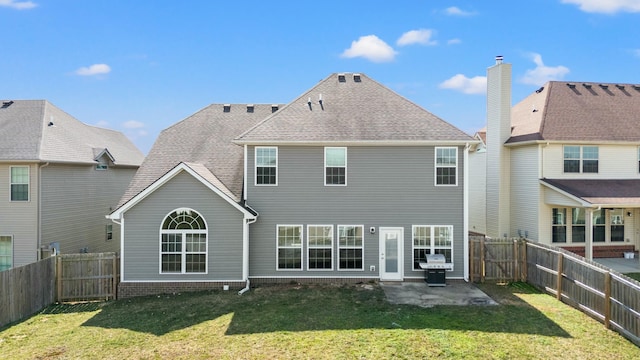 back of house with a patio area, a lawn, a fenced backyard, and roof with shingles