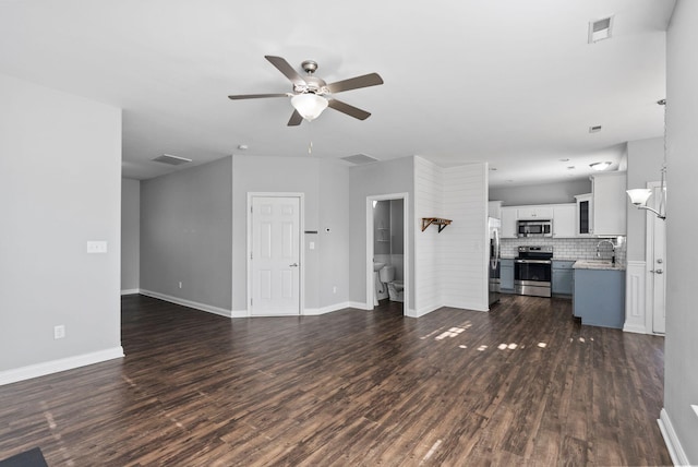 unfurnished living room featuring a sink, visible vents, baseboards, and dark wood-style flooring