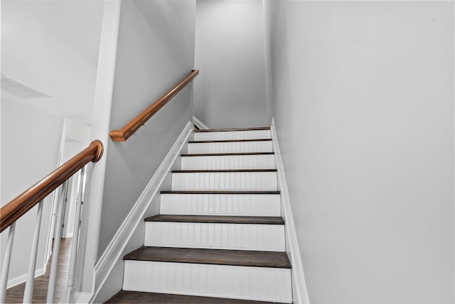 stairs with wood finished floors, visible vents, and baseboards