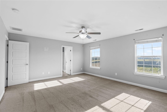 unfurnished room with carpet, visible vents, and baseboards