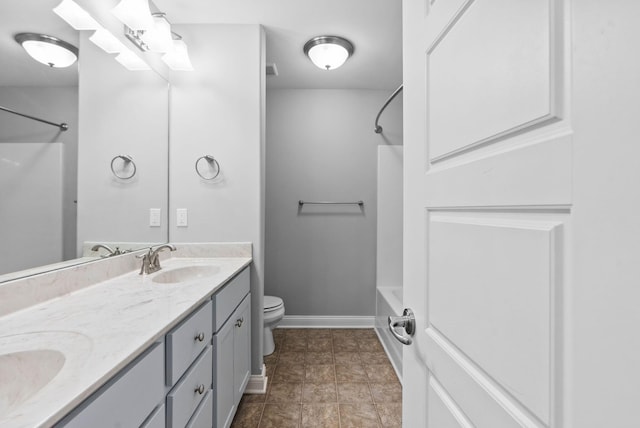 full bathroom with double vanity, toilet, bathtub / shower combination, and a sink