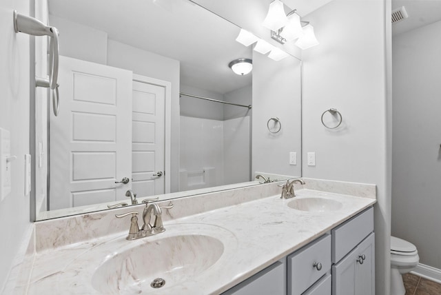 bathroom with a sink, baseboards, toilet, and double vanity