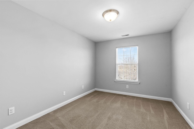 carpeted spare room with visible vents and baseboards