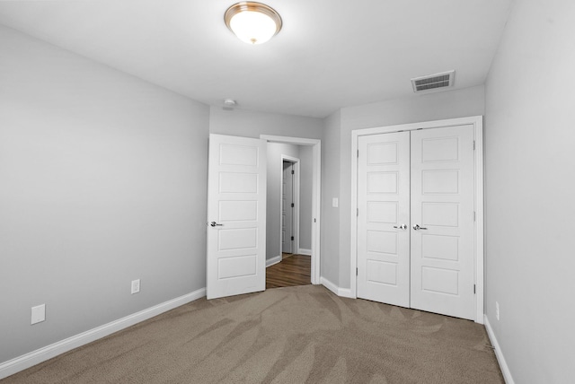 unfurnished bedroom featuring visible vents, baseboards, carpet, and a closet