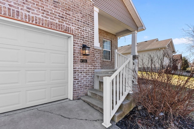 entrance to property featuring a garage and brick siding