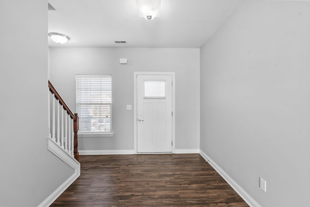 foyer entrance with dark wood finished floors, stairway, baseboards, and visible vents