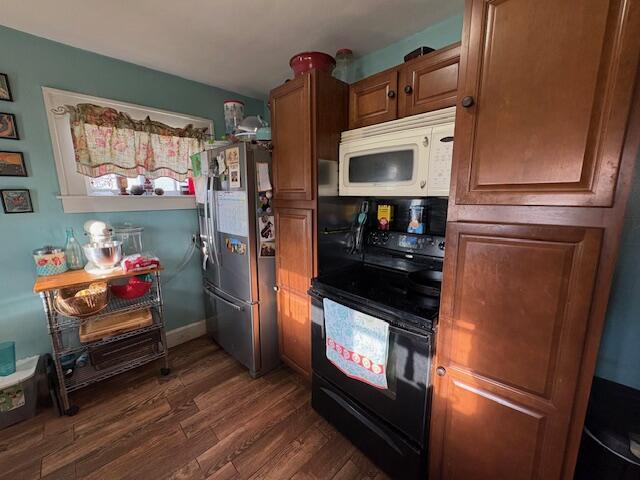 108 Linden Ave, Frankfort, KY 40601 - kitchen featuring dark wood-type flooring, black range with electric cooktop, freestanding refrigerator, white microwave, and brown cabinets