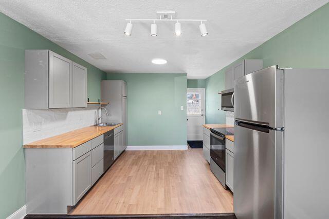 kitchen with stainless steel appliances, decorative backsplash, and gray cabinets