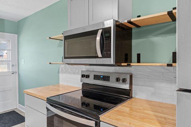 kitchen with open shelves, backsplash, appliances with stainless steel finishes, and white cabinets