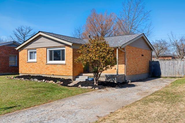 view of side of property with brick siding, a yard, and fence