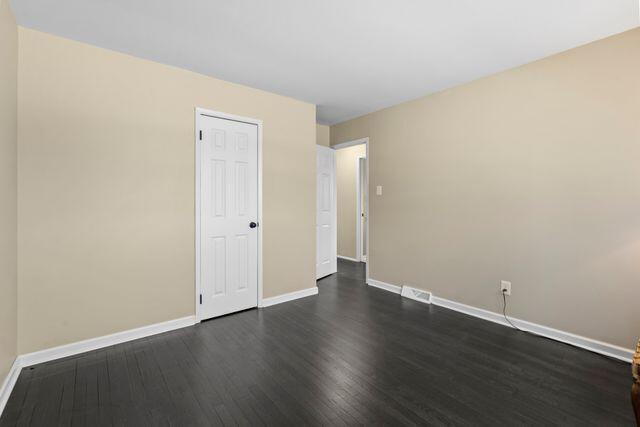 spare room with visible vents, baseboards, and dark wood-style floors