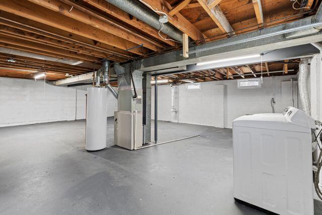 basement with gas water heater, heating unit, and independent washer and dryer