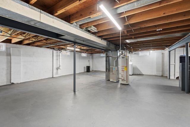 unfinished below grade area featuring gas water heater, heating unit, and washer / dryer