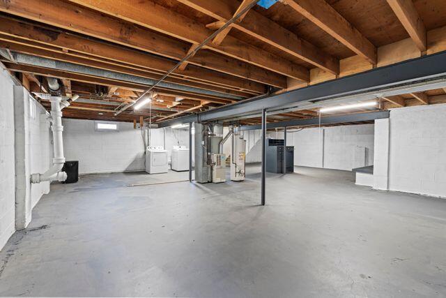 basement with washer and dryer, heating unit, and water heater