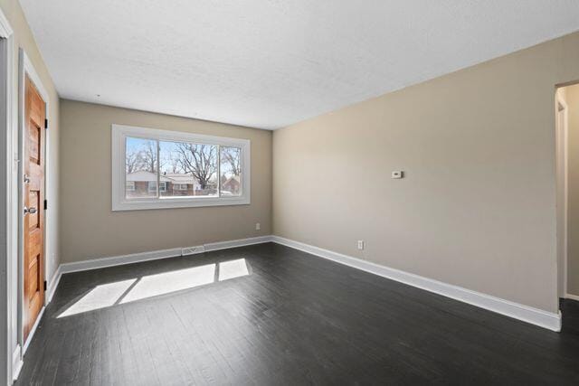 unfurnished room with baseboards and dark wood-style floors