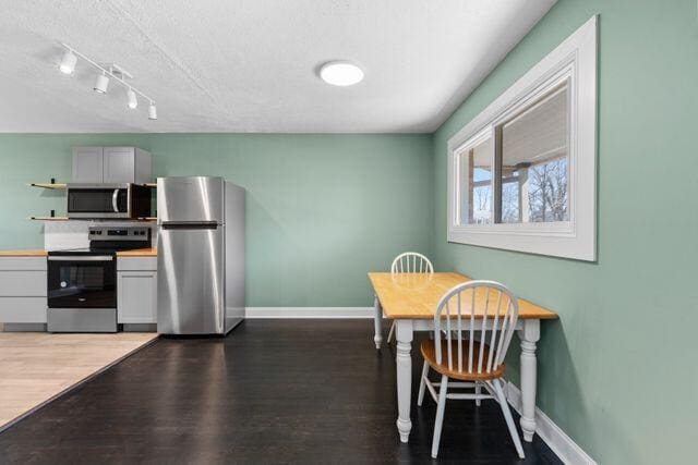 dining room with wood finished floors, baseboards, and a textured ceiling