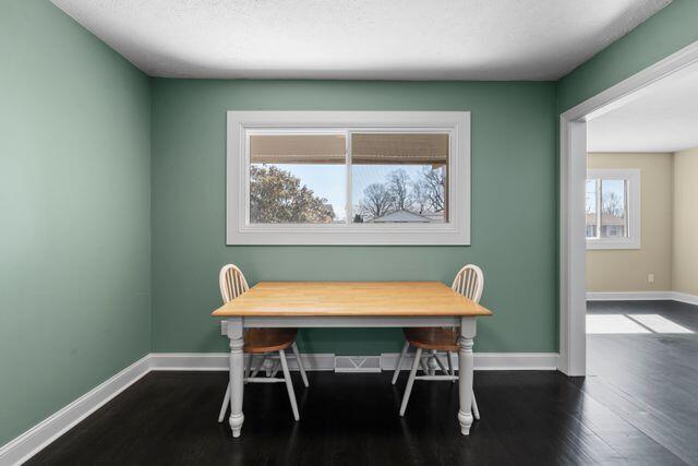 dining area with baseboards, dark wood-type flooring, and a textured ceiling