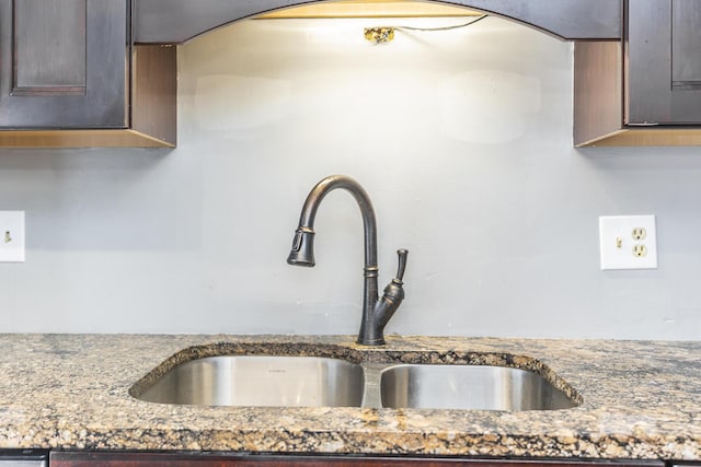 interior details with dark stone countertops, dark brown cabinets, and a sink