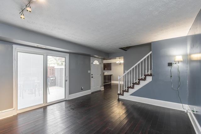 unfurnished living room featuring stairway, baseboards, dark wood-style flooring, a textured ceiling, and a chandelier