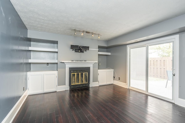 unfurnished living room featuring baseboards, dark wood-type flooring, a glass covered fireplace, and a textured ceiling