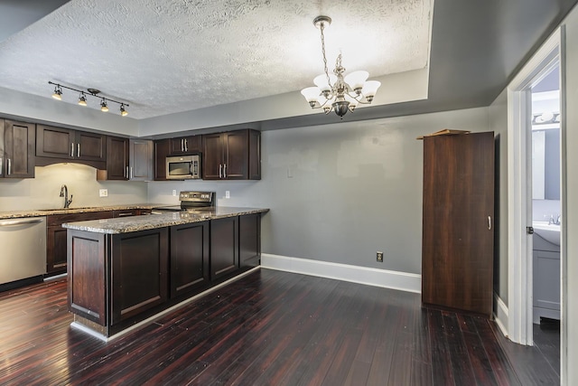 kitchen with a chandelier, stainless steel appliances, dark wood-style floors, a textured ceiling, and a sink