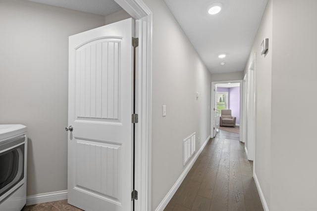 hallway with wood finished floors, washer / clothes dryer, baseboards, and visible vents