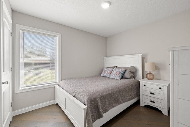 bedroom with baseboards, a textured ceiling, and dark wood-style flooring