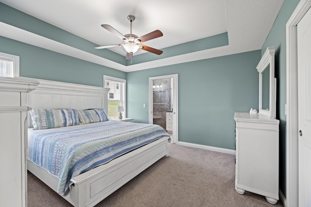 bedroom featuring light colored carpet, baseboards, a tray ceiling, and a ceiling fan