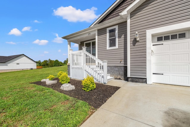 view of exterior entry with an attached garage, concrete driveway, and a yard