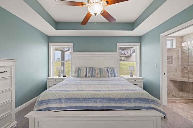 bedroom with a tray ceiling, baseboards, connected bathroom, and carpet flooring