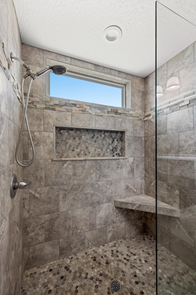 bathroom featuring a textured ceiling and tiled shower