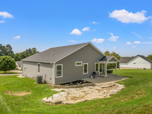 rear view of property with cooling unit, a patio, a lawn, and a shingled roof