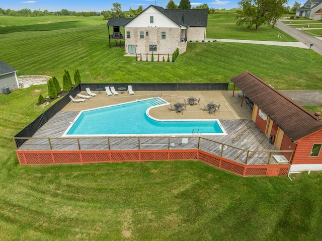 pool with a patio area, a lawn, and fence