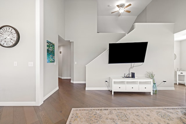 living room featuring baseboards, a high ceiling, ceiling fan, and wood finished floors