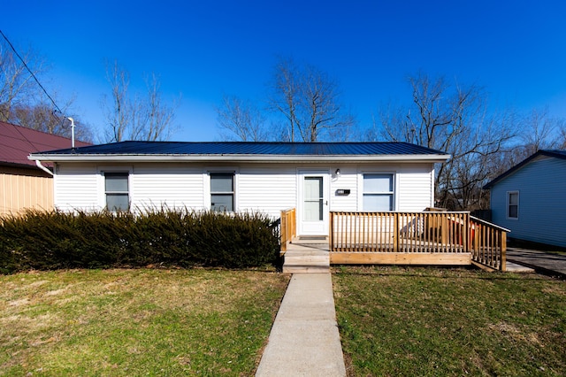 view of front facade featuring a deck, metal roof, and a front yard