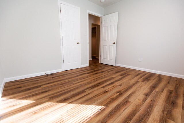 unfurnished bedroom featuring wood finished floors and baseboards