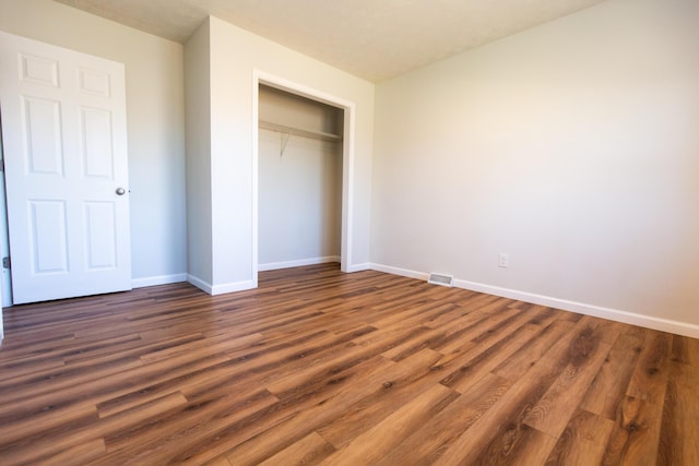 unfurnished bedroom with a closet, baseboards, and wood finished floors