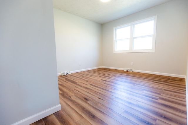 spare room with visible vents, baseboards, and wood finished floors