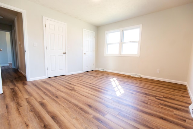 unfurnished bedroom featuring visible vents, baseboards, and wood finished floors