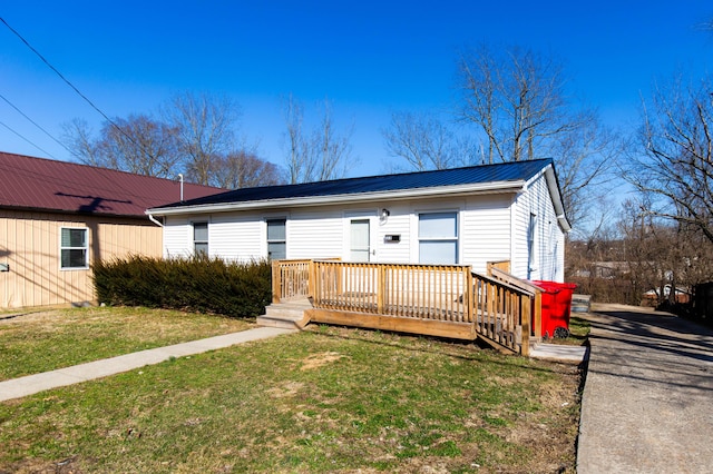 view of front of home with a deck, metal roof, and a front lawn