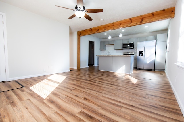 kitchen featuring a sink, baseboards, appliances with stainless steel finishes, and light wood finished floors