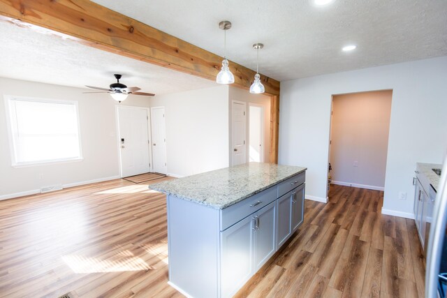 kitchen featuring light stone countertops, baseboards, hanging light fixtures, light wood-style floors, and a center island