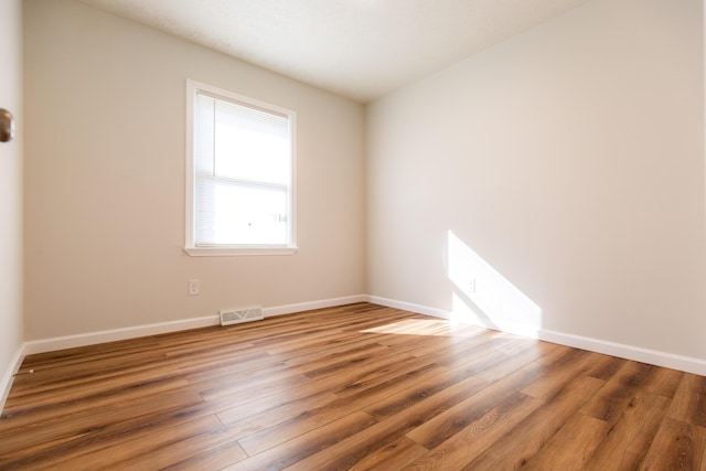 empty room with visible vents, baseboards, and wood finished floors